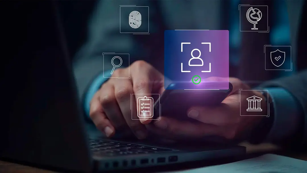 Pessoa utilizando um celular sobre um notebook