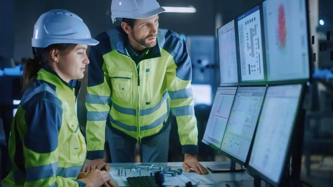 Um homem e uma mulher com equipamento de segurança olhando para monitores